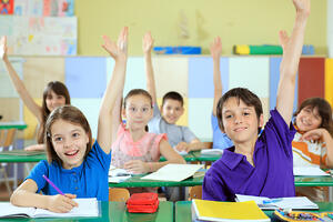 Elementary-school-students-raising-hands-in-classroom_